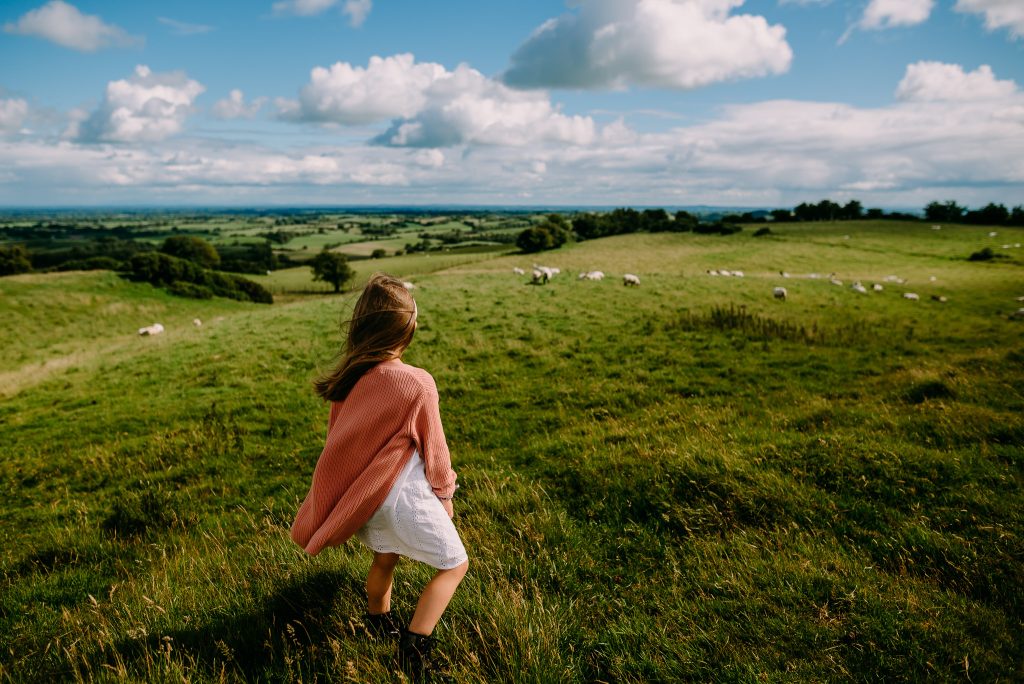 Girl watching the sheep in the field in the distance