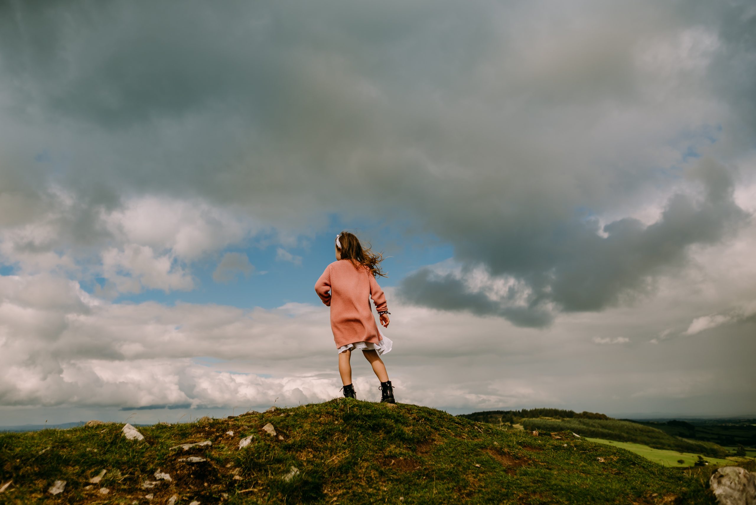 Girl on the mountain with beautiful sky in front of her