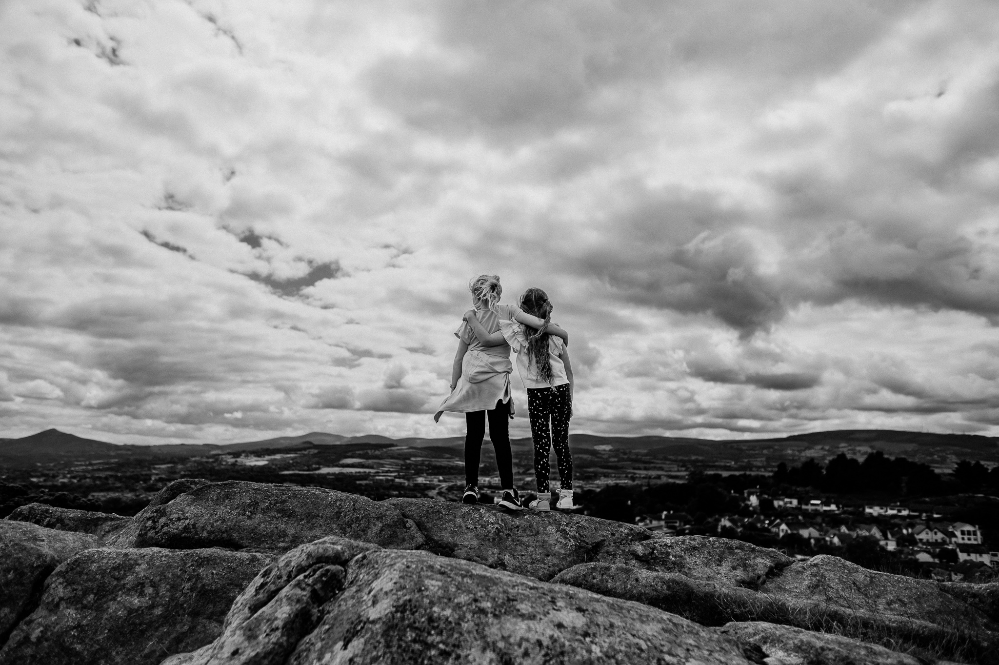 Girls embracing on the mountain with beautiful sky behind them